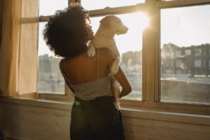 black woman holding dog near window