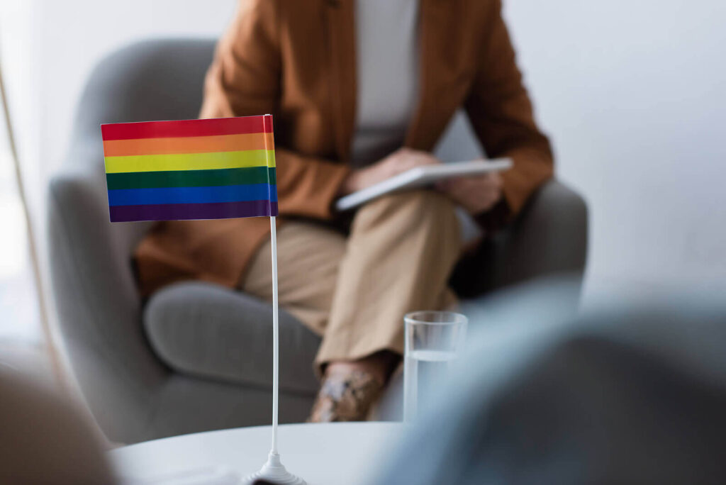 A therapist with an LGBTQ+ flag on her table who is facilitating an LGBTQ+ Process Group during Group Therapy in Pasadena, CA. Therapy groups offer a safe and comfortable environment to connect with others.